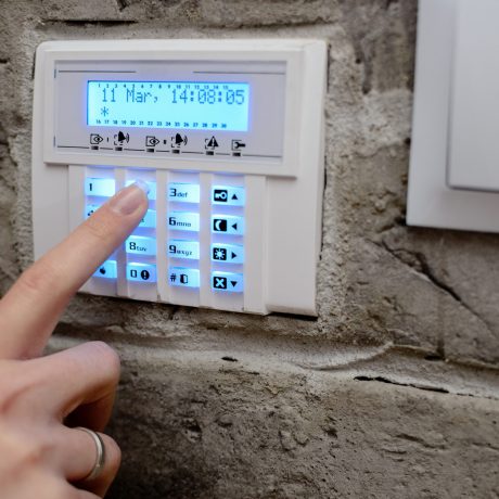 Closeup on woman's finger entering code into the keypad of the alarm system and activates the alarm